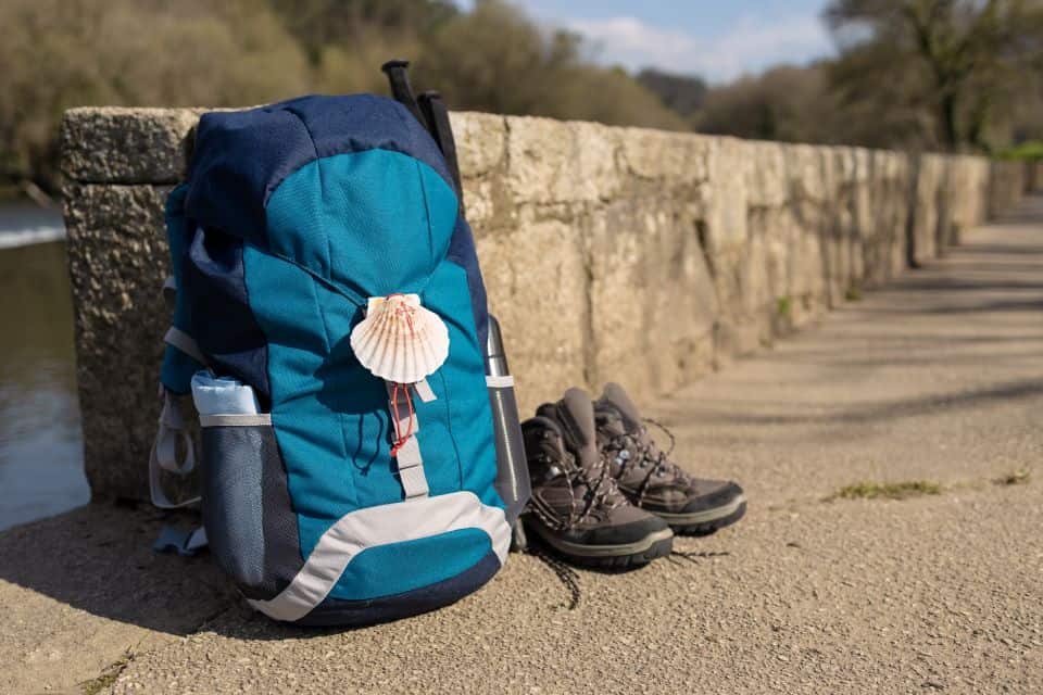 mochila-con-concha-en-el-suelo-junto-botas-senderismo-camino-de-santiago